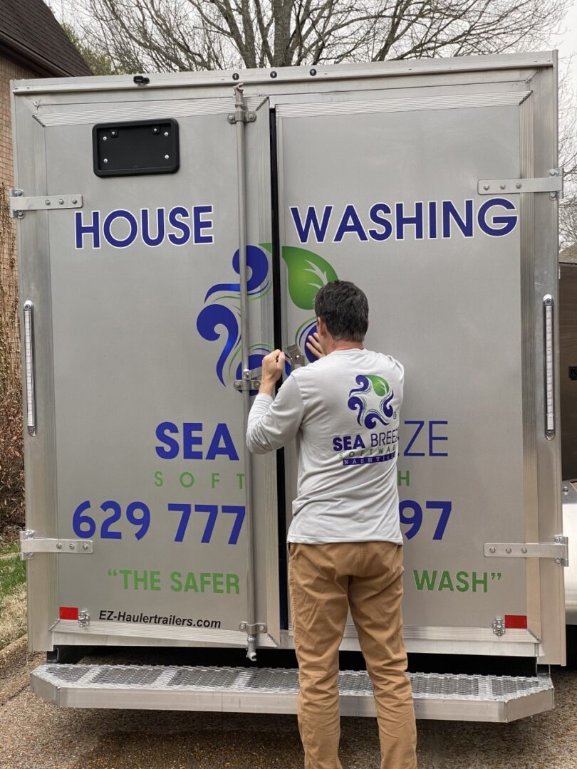A man is painting the side of a truck.